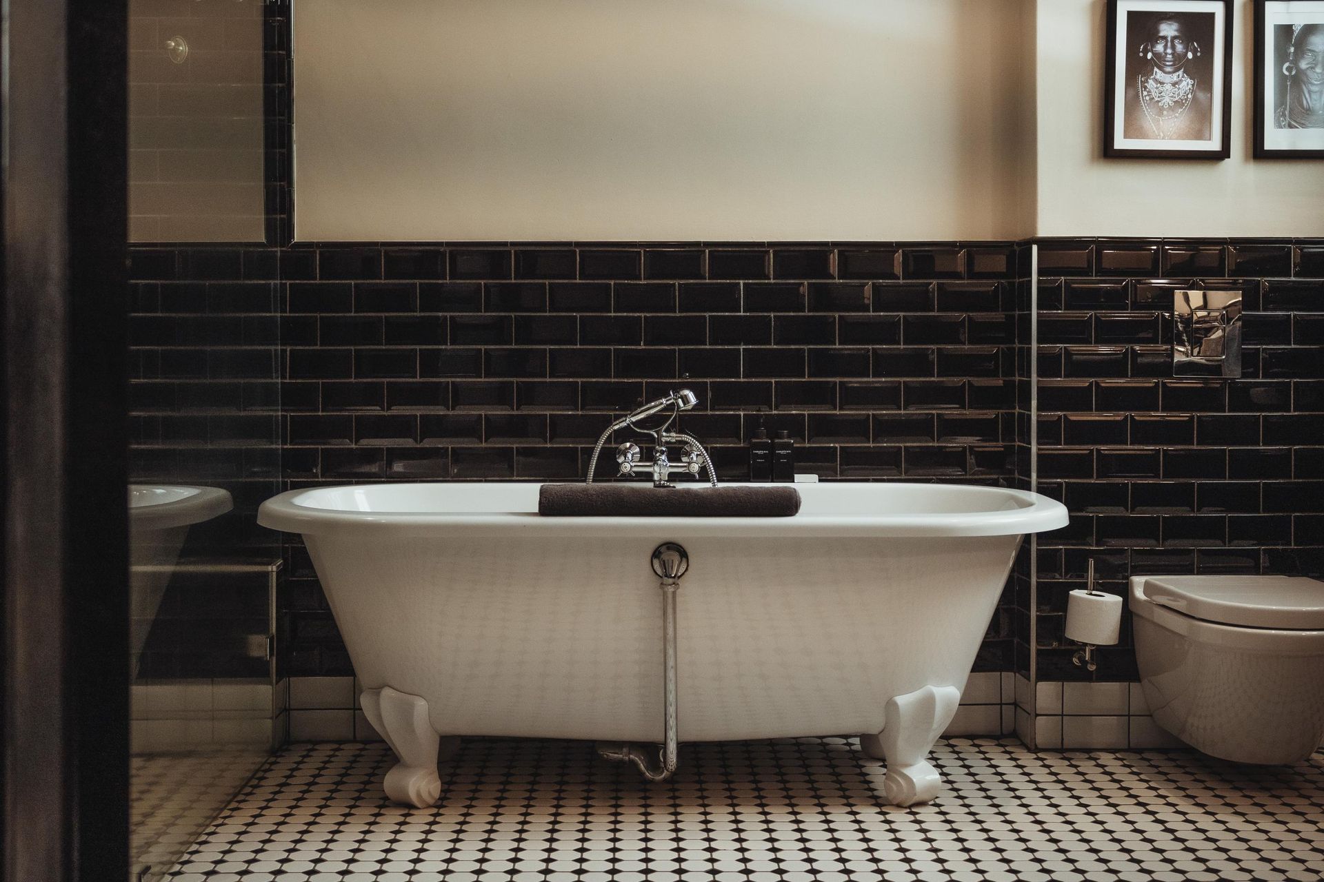a bathroom with black tiles and a white bathtub