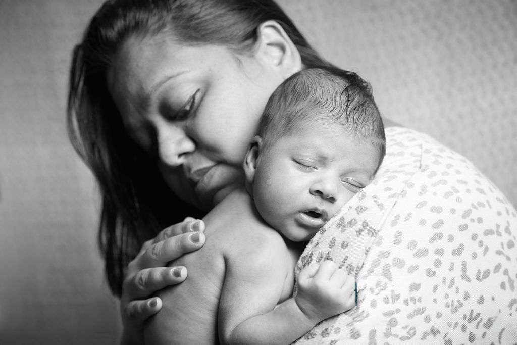 Mother holding yawning baby in a softly lit room