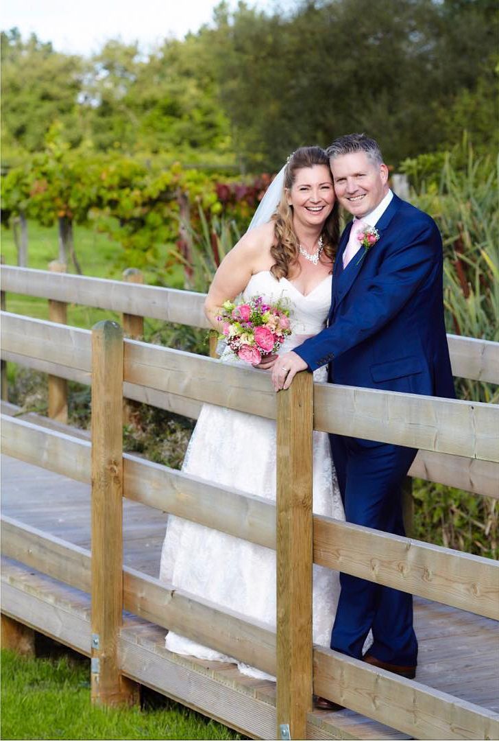 Bride and groom kissing at an outdoor wedding, with bridesmaids in blue dresses around them