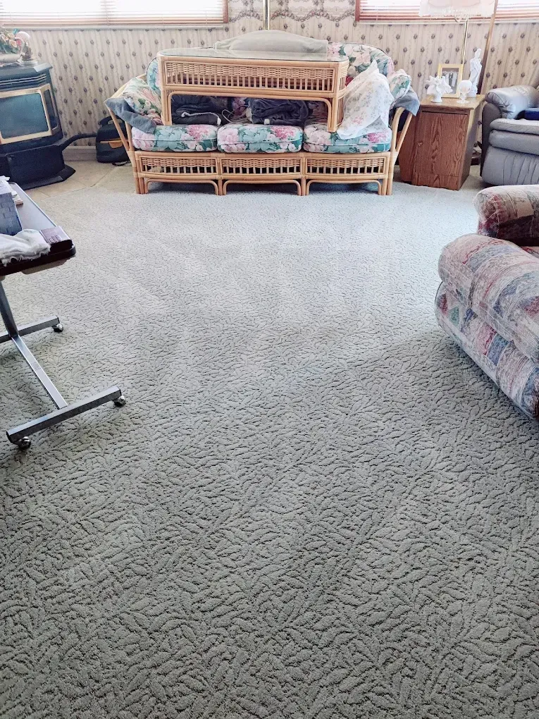 Living room with patterned carpet and furniture, including a wicker sofa.