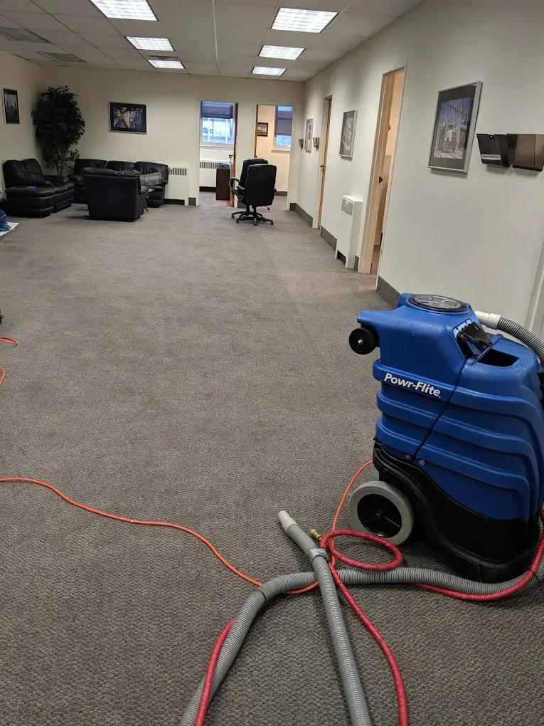 Blue carpet cleaner in an office cleaning a gray carpet.