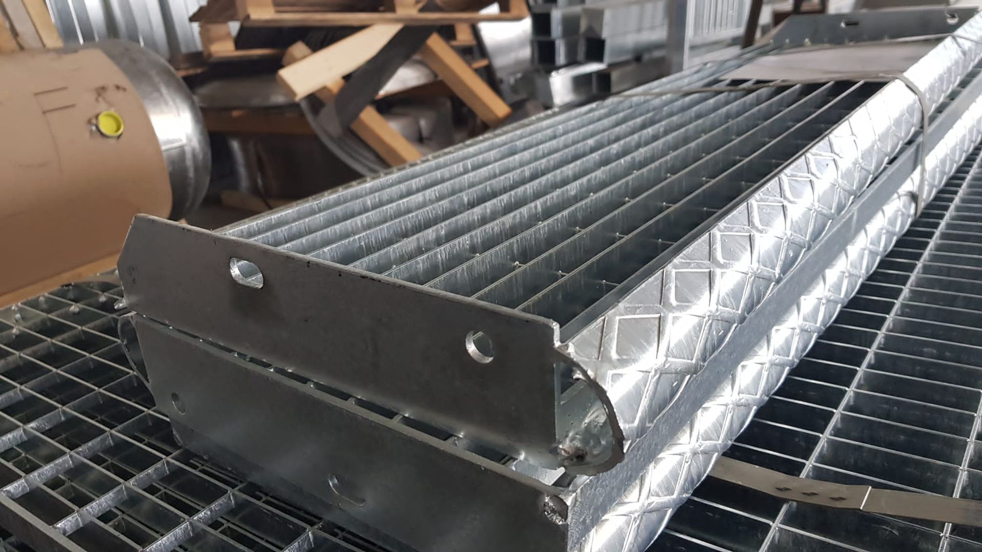 Assemblaggio di rulli metallici per trasportatori industriali su un banco da lavoro in un'officina.