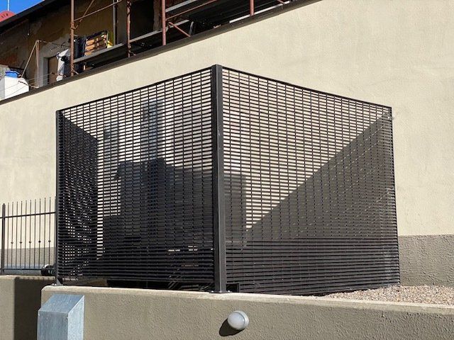 Recinto in metallo nero accanto al muro di un edificio beige all'aperto