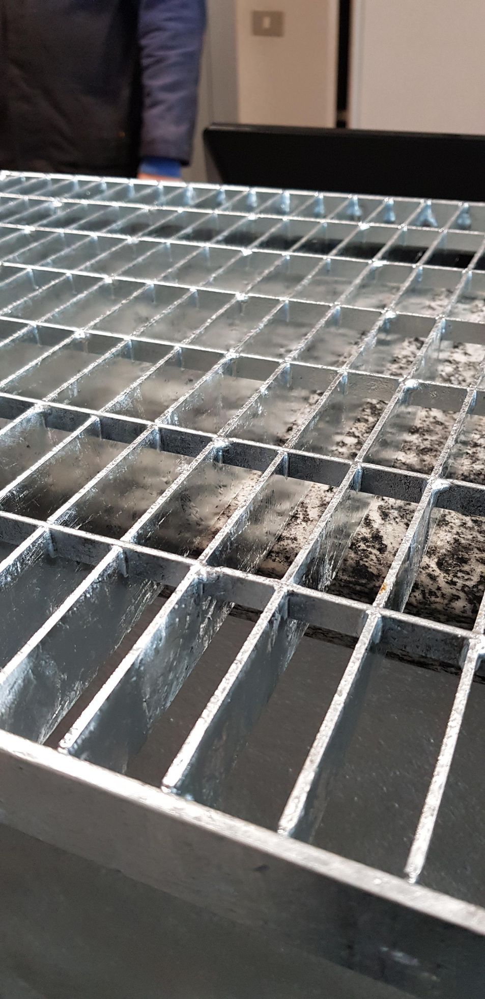 Griglia metallica con acqua sottostante, vista da un'angolazione diversa.
