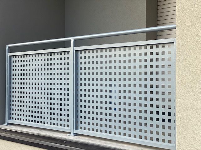 Ringhiera per balcone in metallo grigio con pannelli perforati e corrimano orizzontale