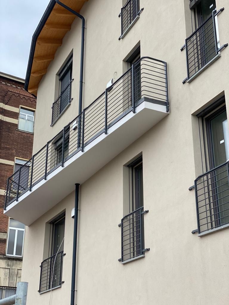 Esterno di un condominio con pareti beige, balconi e finestre con inferriate.