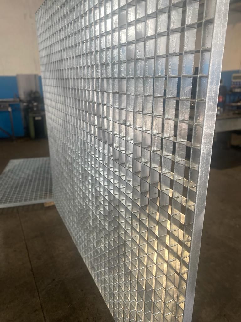 Parete in blocchi di vetro trasparente in un'officina industriale con attrezzature blu sullo sfondo.