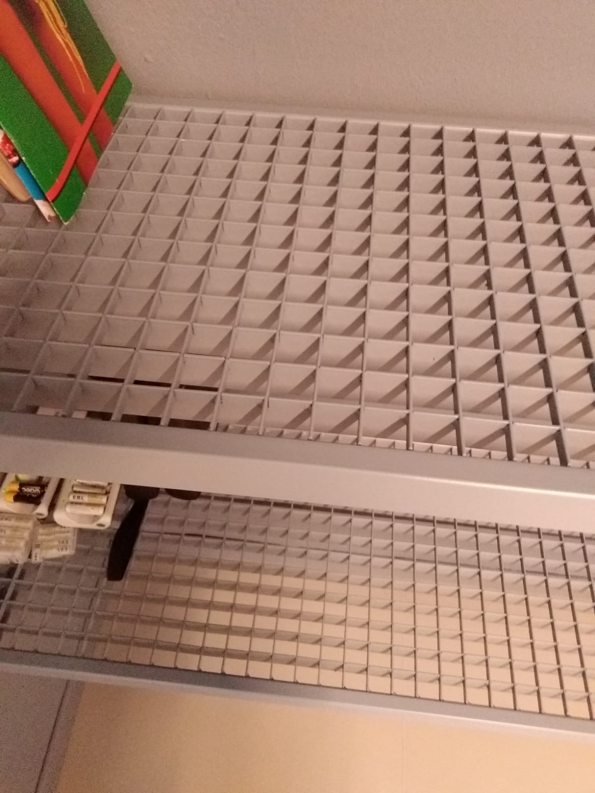 Soffitto in rete metallica con una struttura rosso vivo e verde nell'angolo in alto a sinistra.