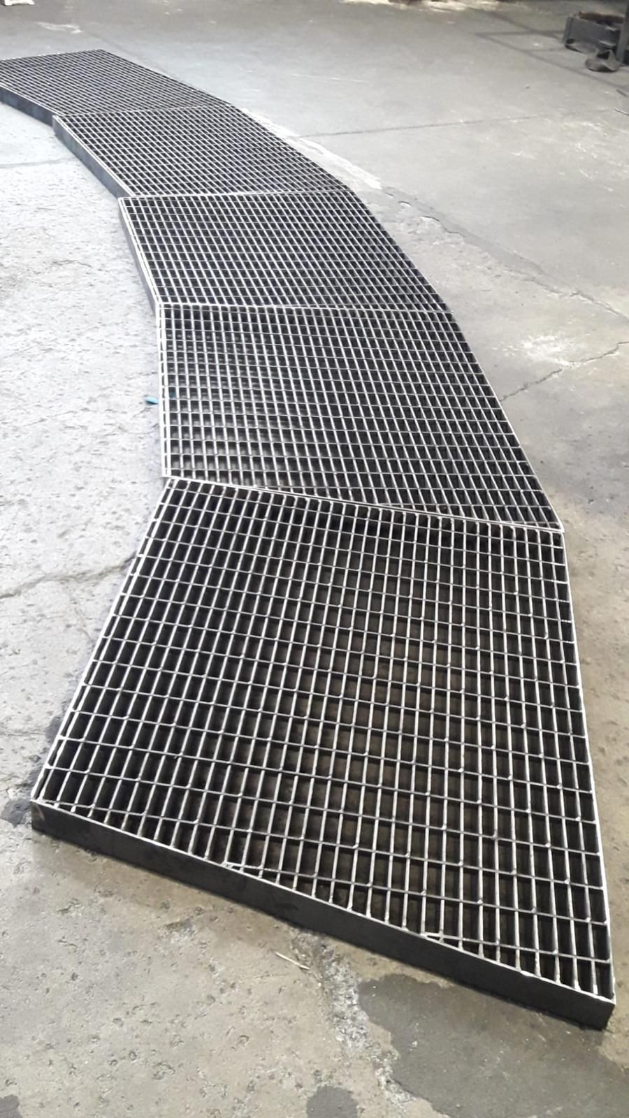 Rampa o passerella curva in metallo nero su un pavimento di cemento all'interno di un magazzino.