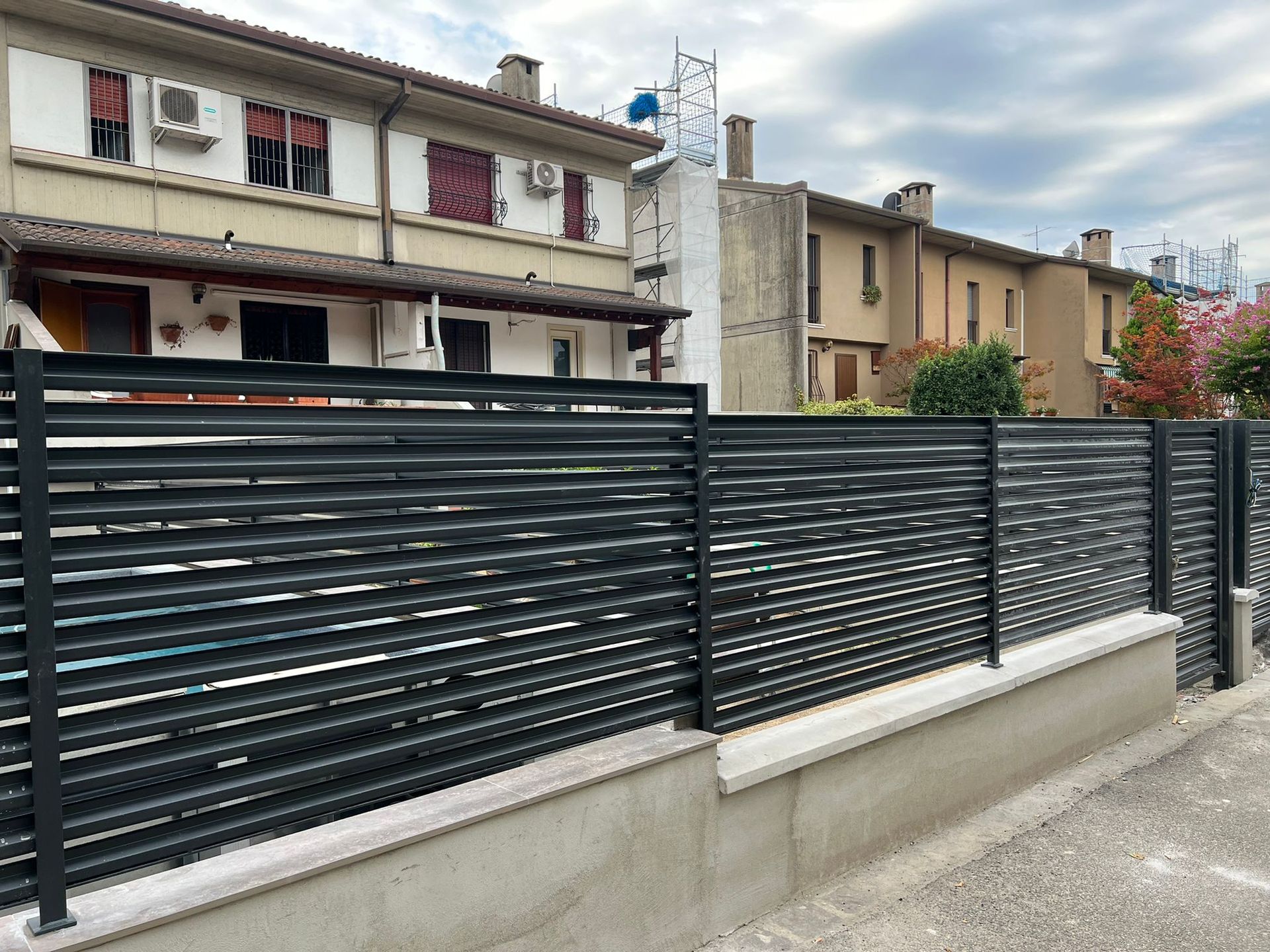 Recinzione metallica scura di fronte agli edifici residenziali in una strada tranquilla