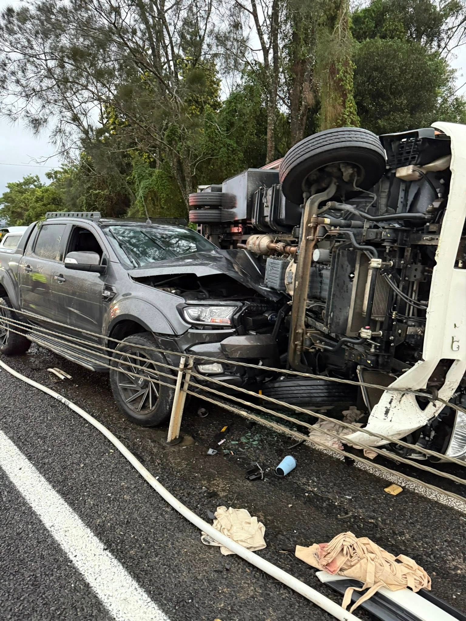 Car and overturned truck on a highway after a collision; dark gray car heavily damaged — Bangalow Towing in Bangalow, NSW