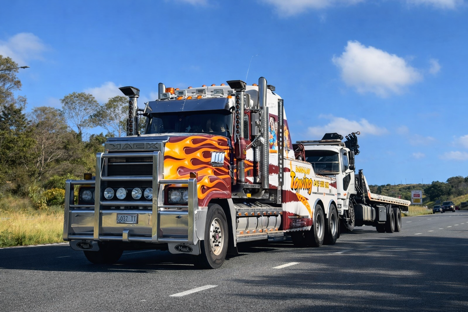 Two colorful tow trucks driving on a highway under a blue sky — Bangalow Towing in Bangalow, NSW