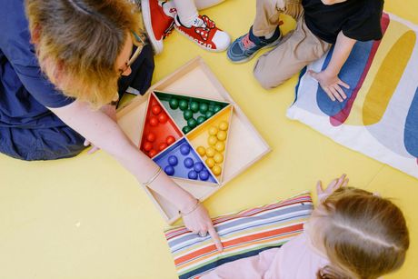 Children arranging colorful triangular beads on a floor play mat