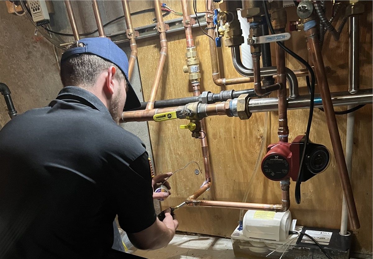 Plumber inspecting copper pipes and valves in a utility room.