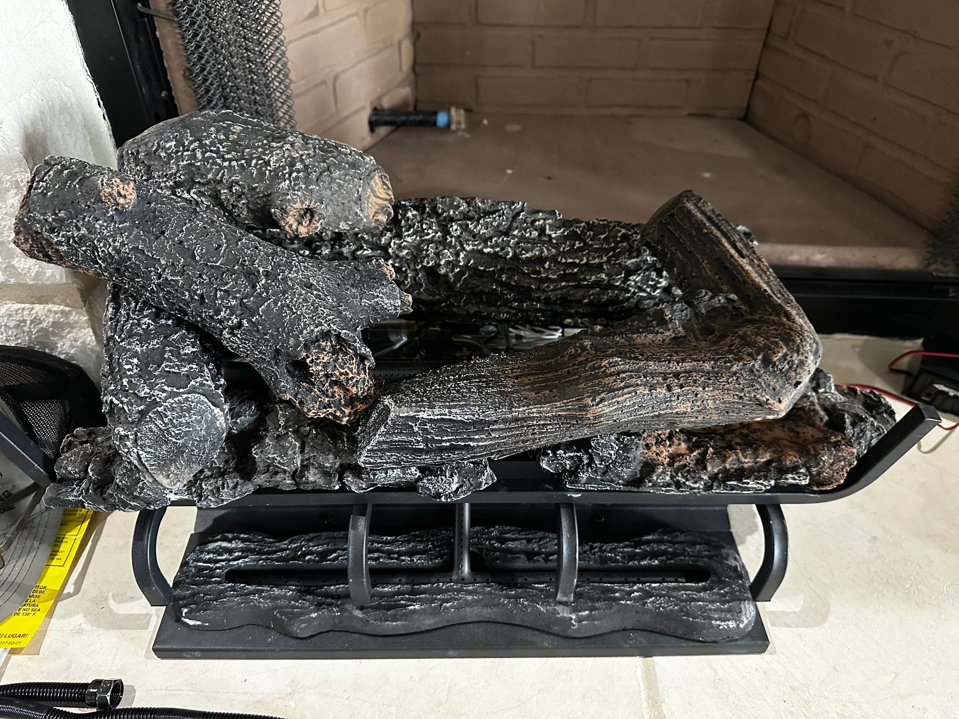 A pile of logs is sitting in front of a fireplace.