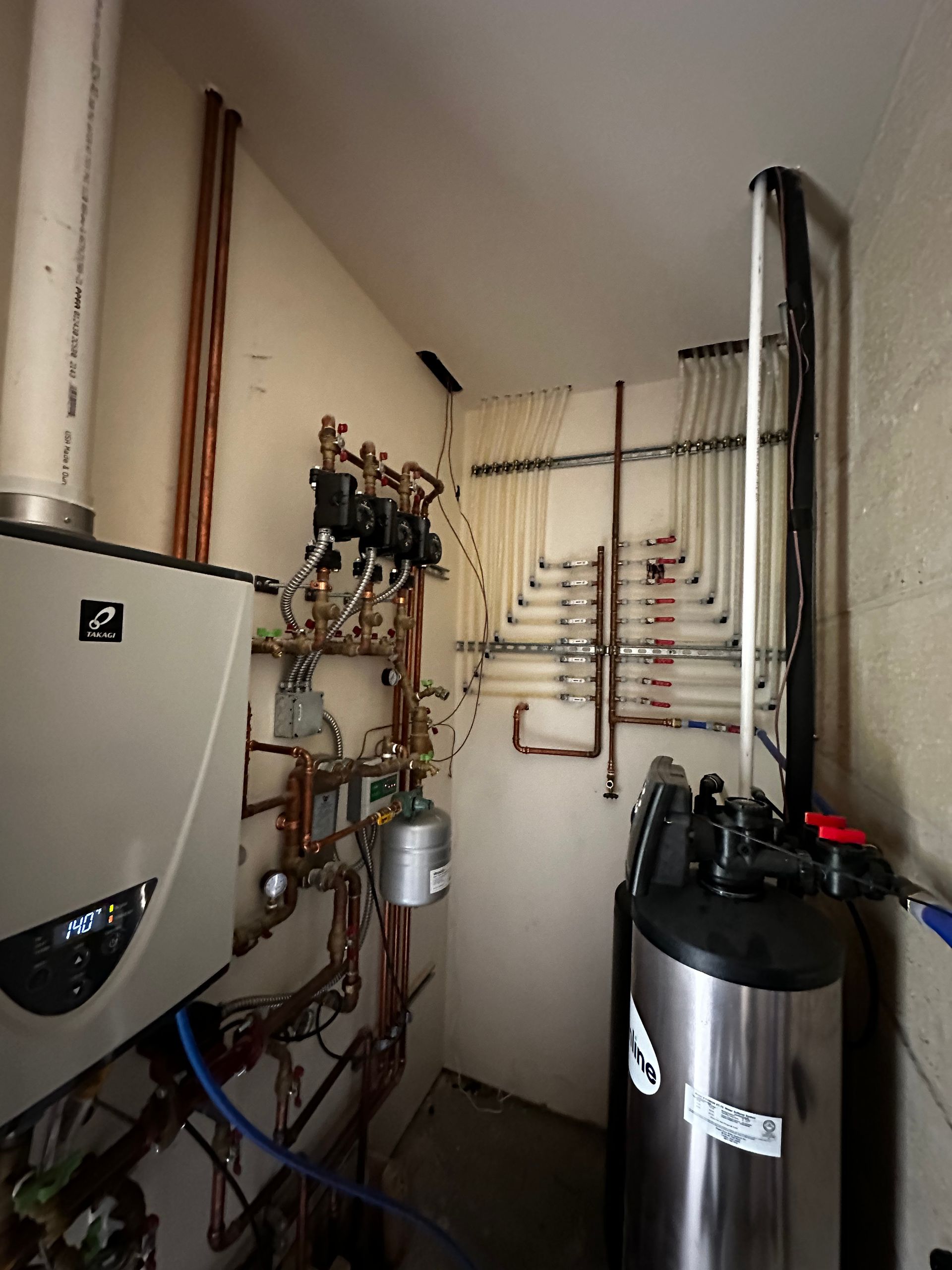 A room with a stainless steel water heater and a boiler