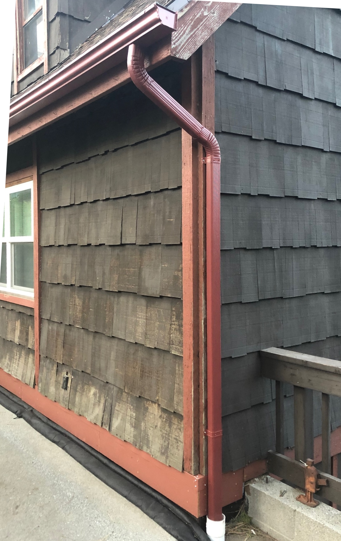 A house with a red gutter on the side of it.