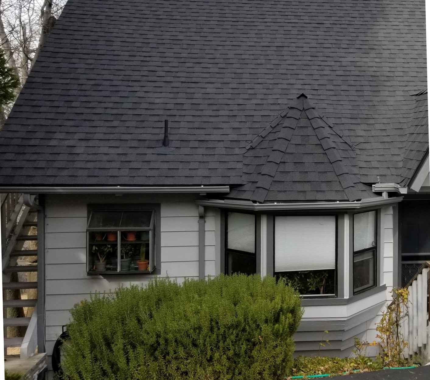 A house with a black roof and a bay window