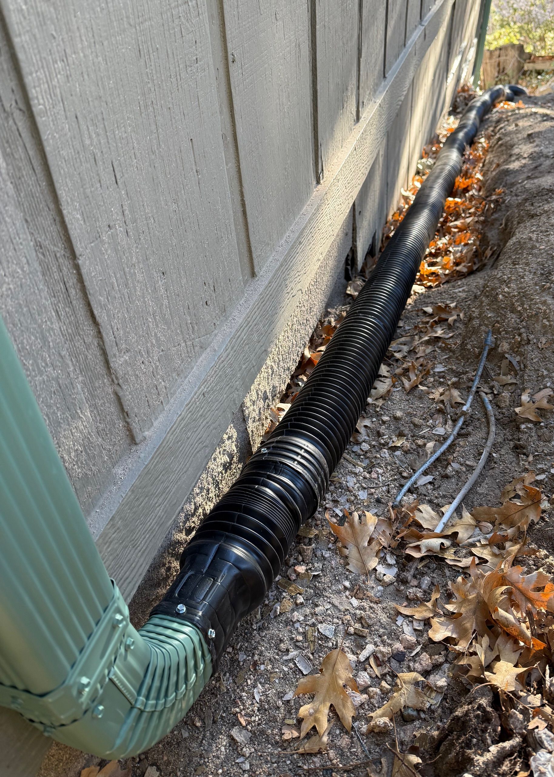 A black drain pipe is sitting next to a brick wall.