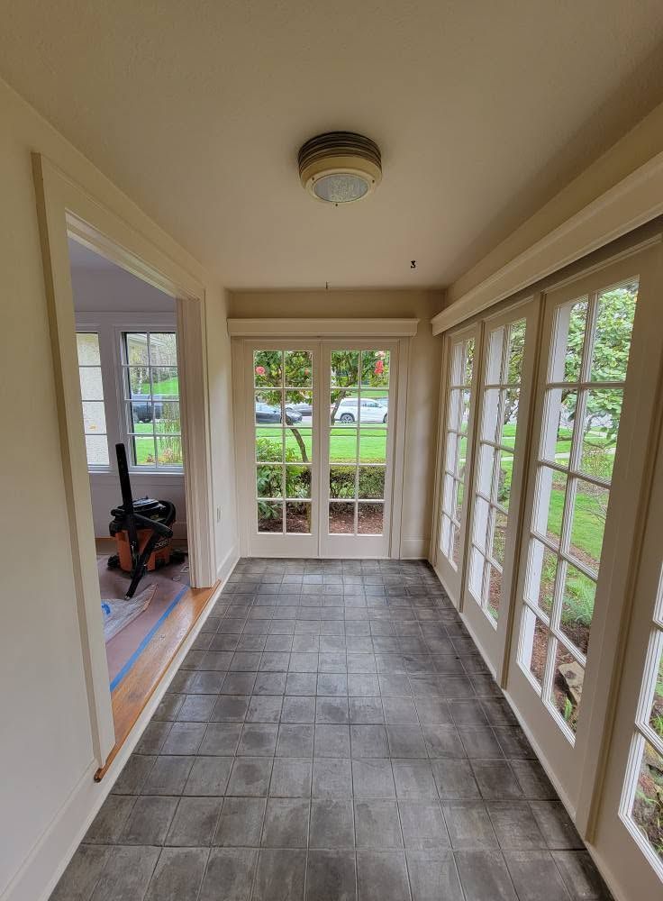 Sunroom hallway with tiled floor, French doors, and windows overlooking a garden