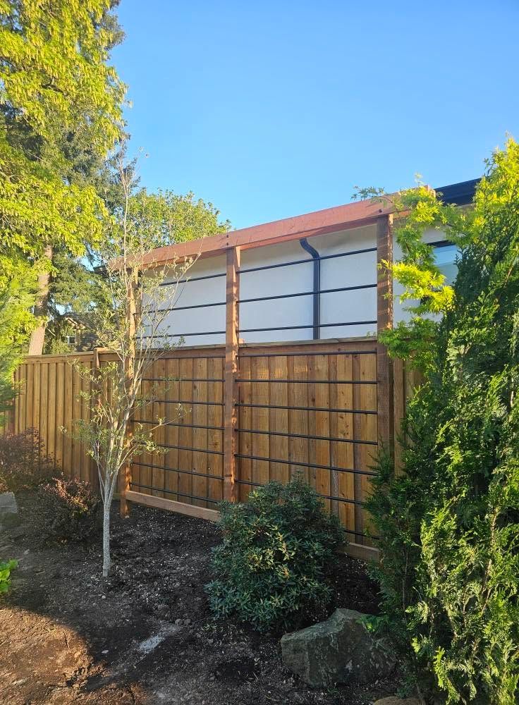 Backyard fence with lattice top, bordered by trees and shrubs under a blue sky