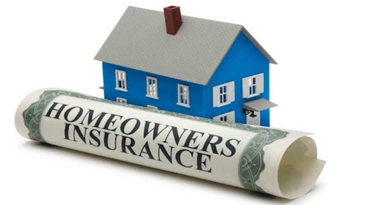 A blue house is sitting on top of a roll of homeowners insurance