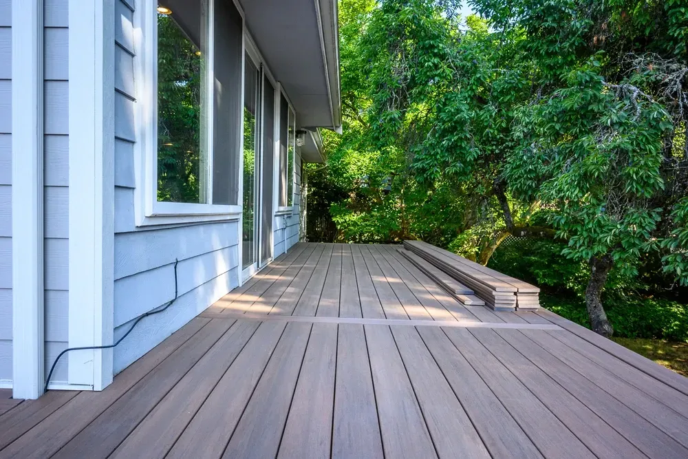Wooden deck alongside a light blue house, surrounded by trees. — Dimond J Carpentry in Bli Bli, QLD