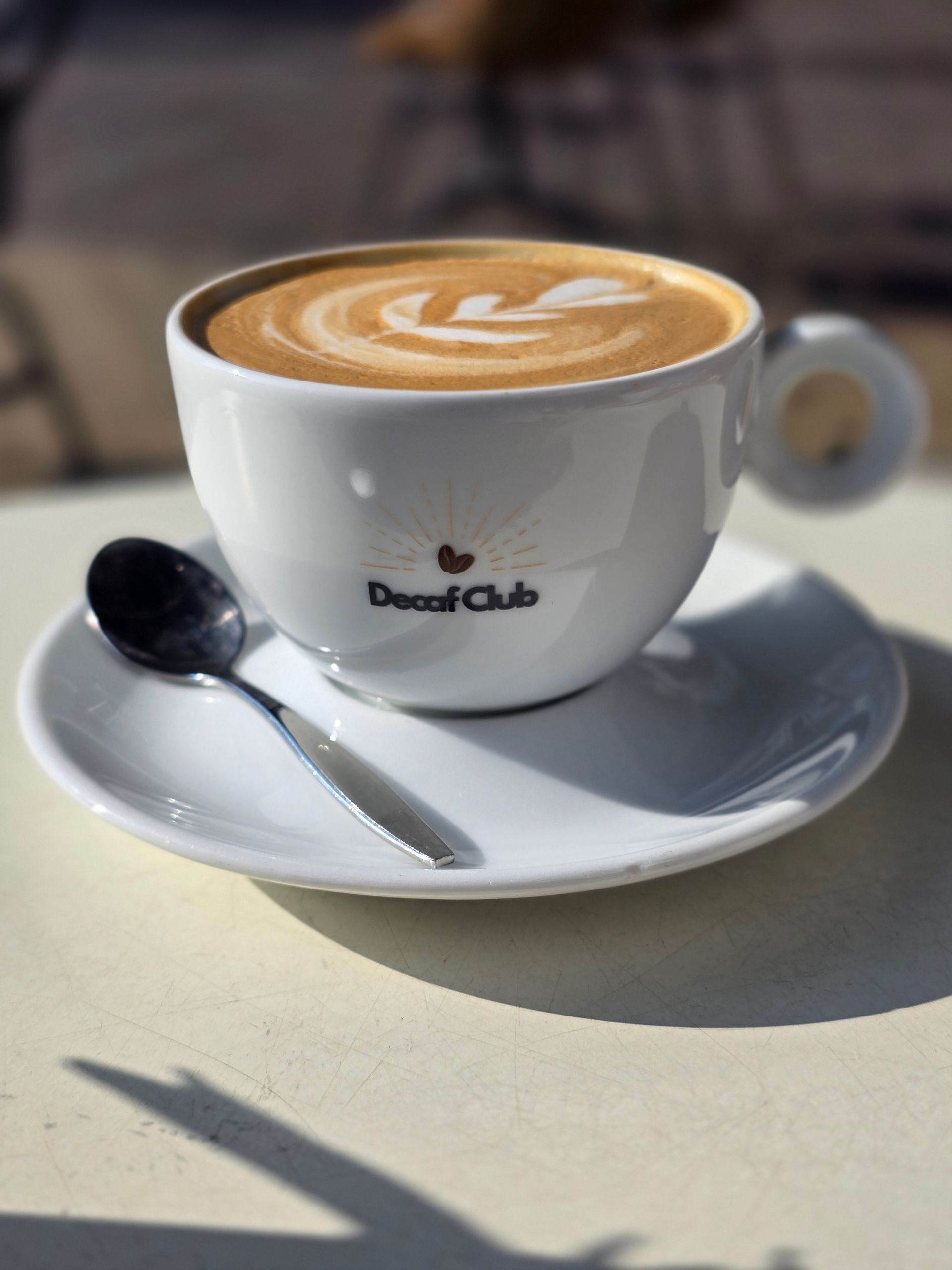 Kopje latte met latte art op een schoteltje en een lepel. 