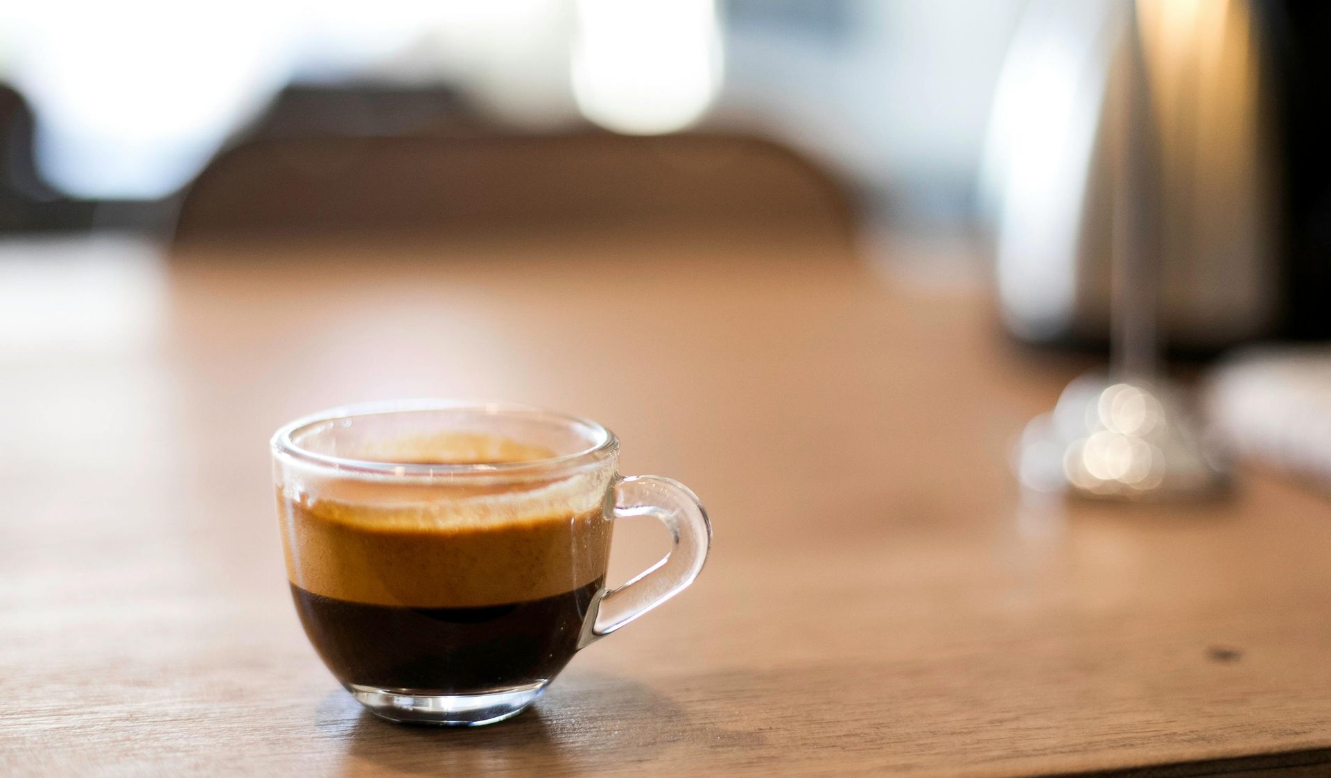 Kopje latte met latte art op een schoteltje en een lepel. 