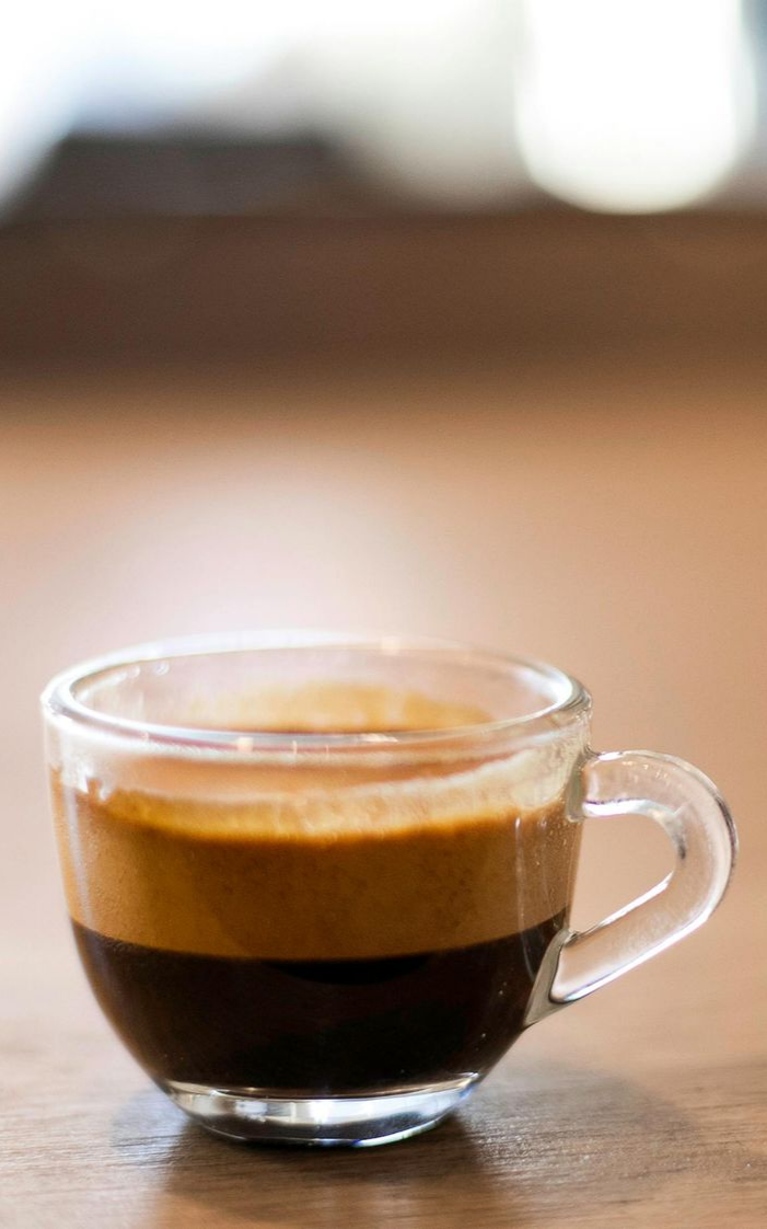 Kopje latte met latte art op een schoteltje en een lepel.