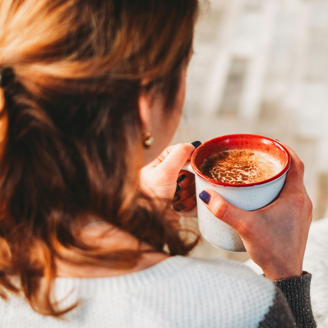 Kopje latte met latte art op een schoteltje en een lepel.