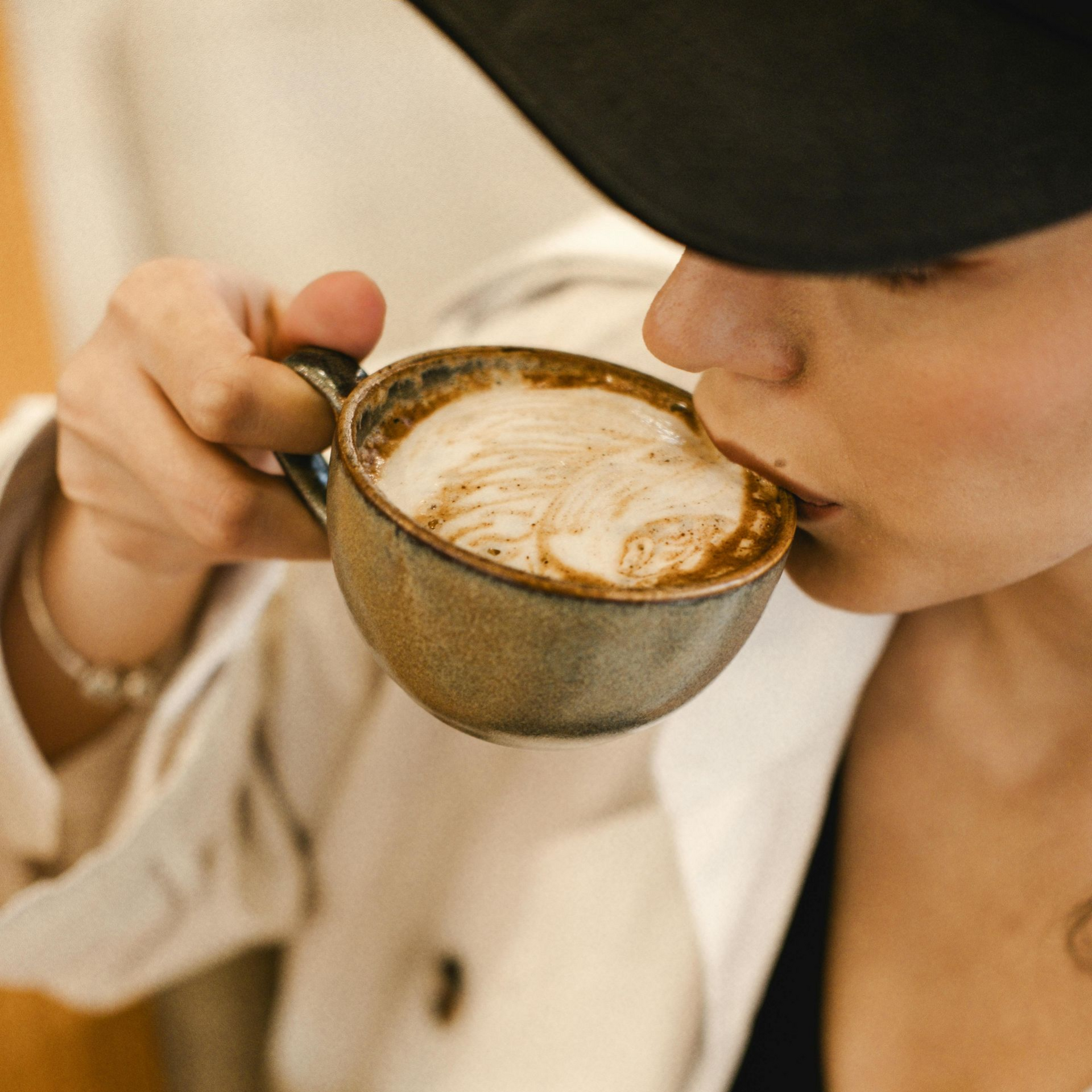Kopje latte met latte art op een schoteltje en een lepel. 