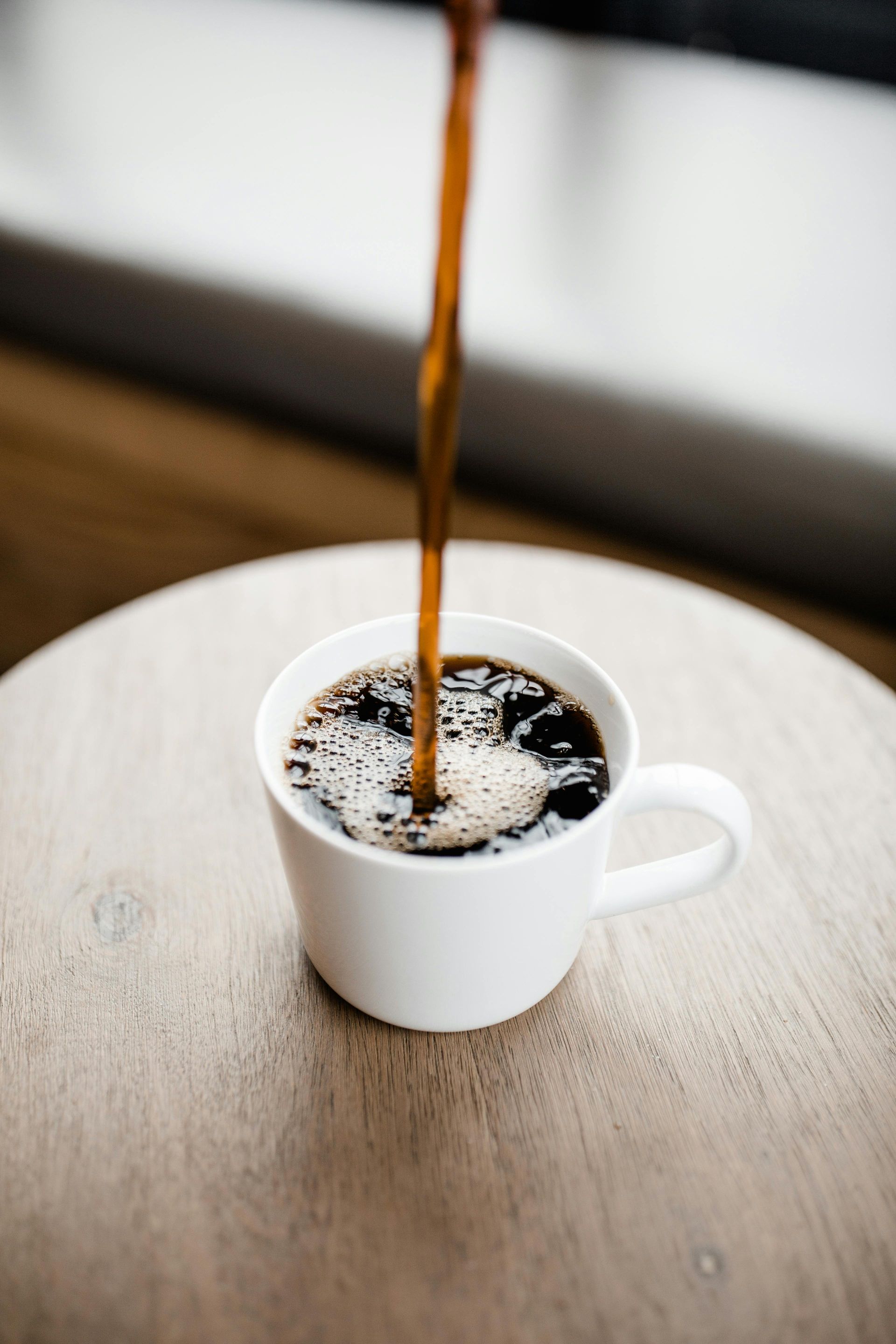 Kopje latte met latte art op een schoteltje en een lepel.