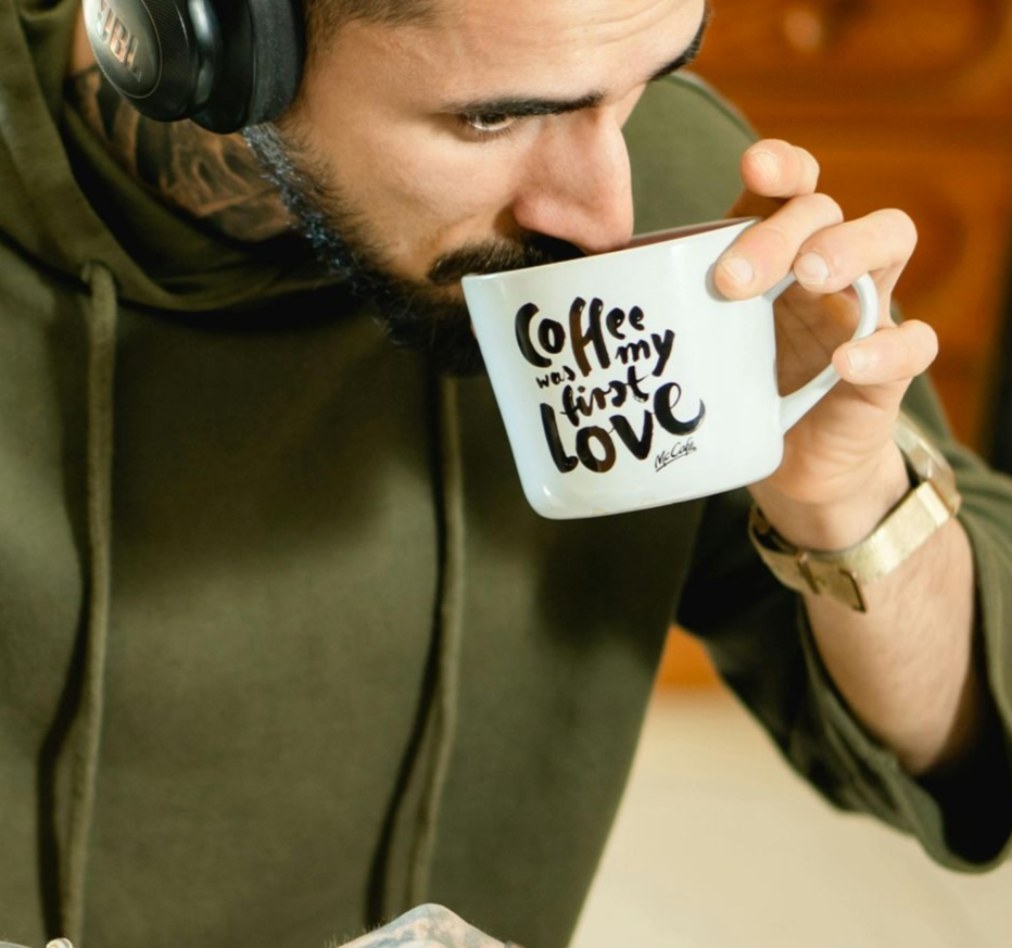 Kopje latte met latte art op een schoteltje en een lepel.