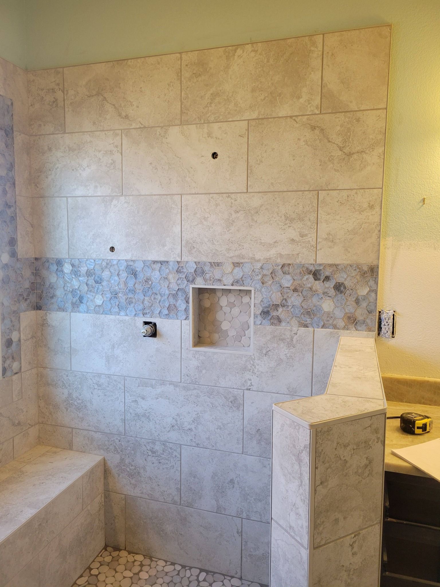 Bathroom under renovation with tiled shower wall, built-in niches, and unfinished surfaces