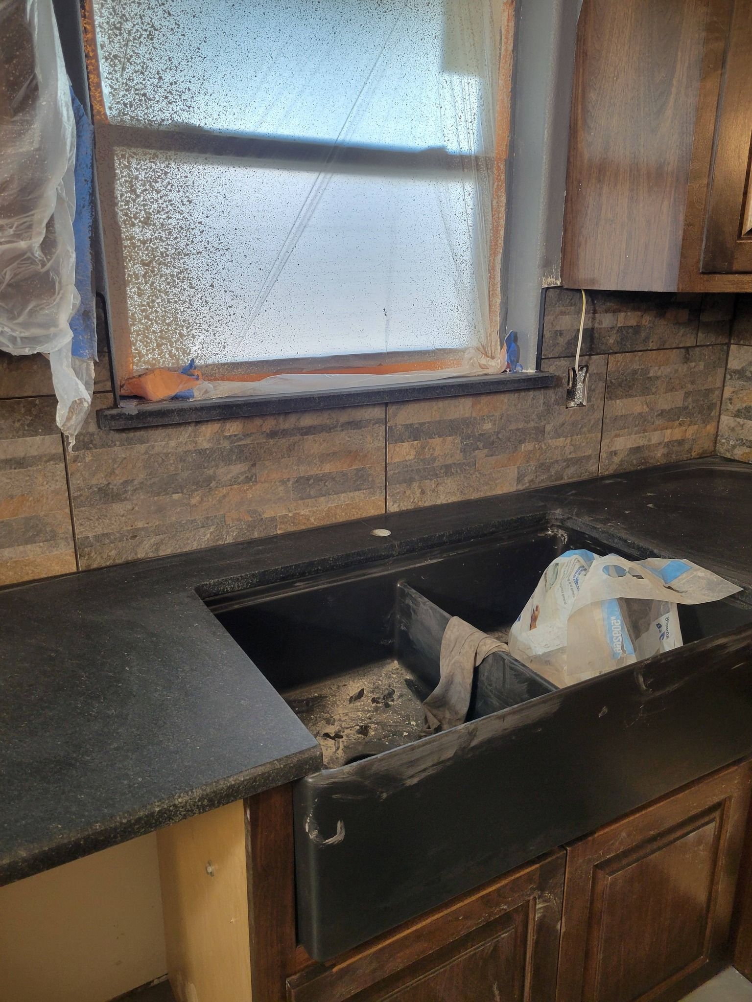 Kitchen sink area under renovation with exposed drywall and a window above the counter