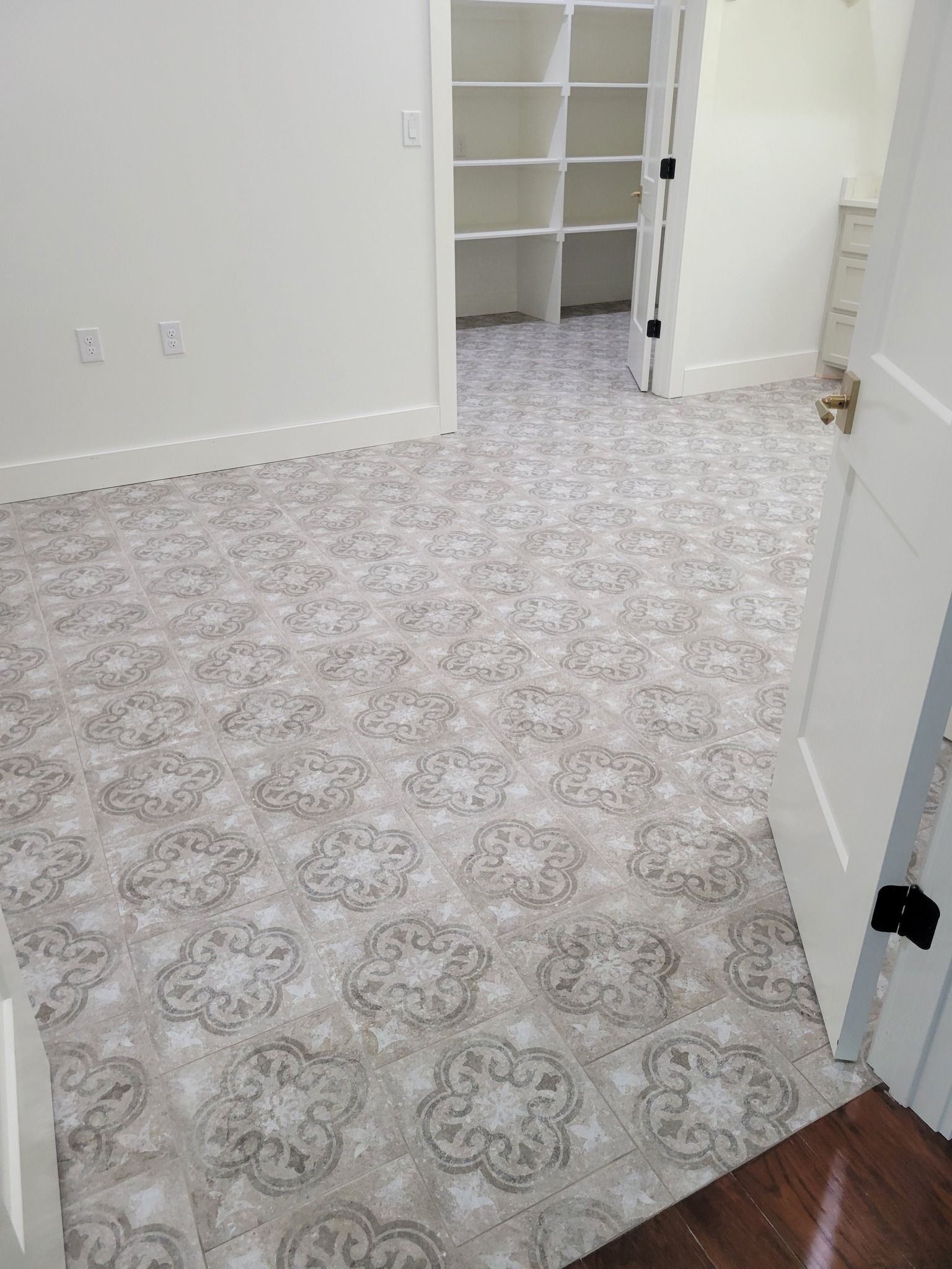 Empty carpeted room with white walls, open closet, and doorway to wood floor hallway
