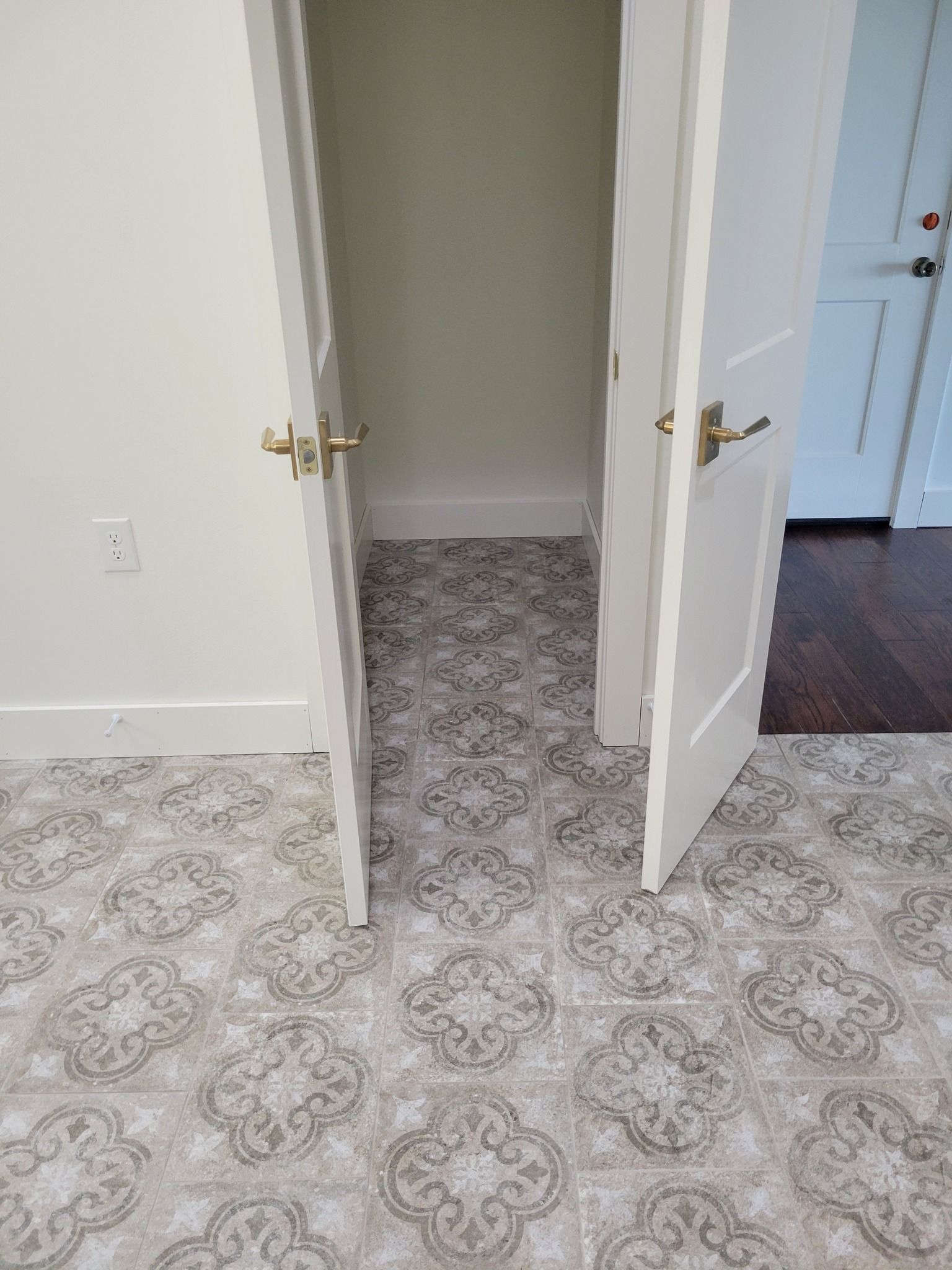 Open double doors to a small closet with patterned carpet and white walls.