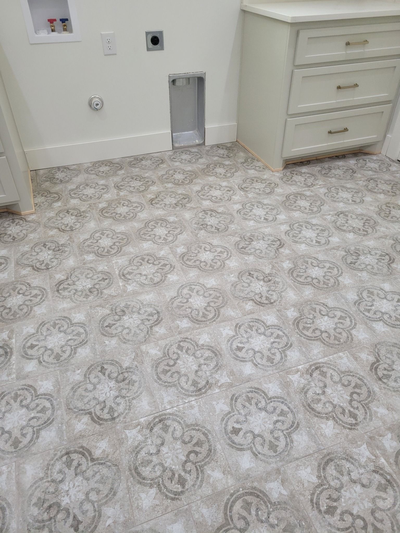 Empty medical exam room with patterned carpet and cabinet drawers along the wall