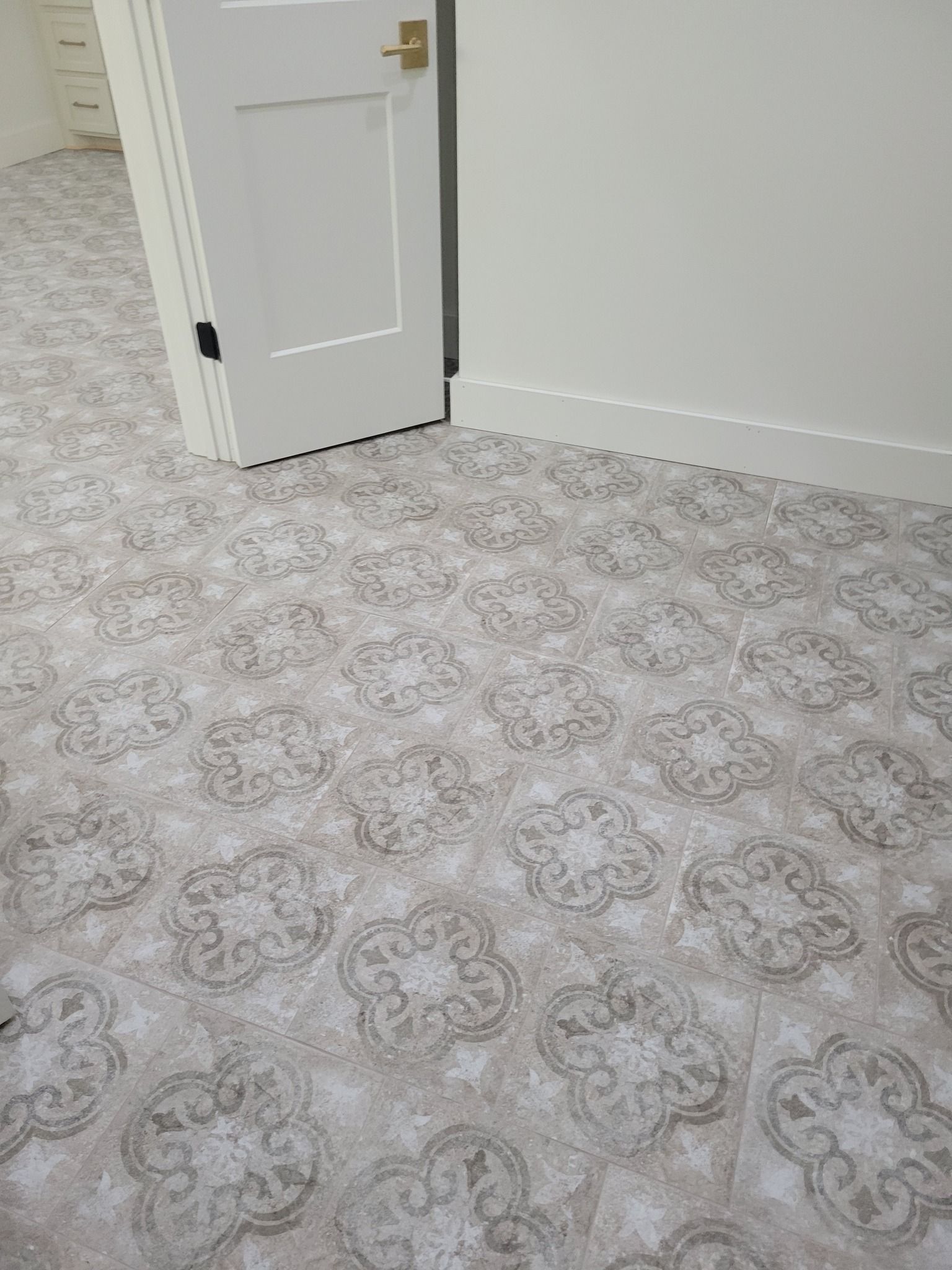 Empty room with light gray patterned carpet, white walls, and a partially open door.