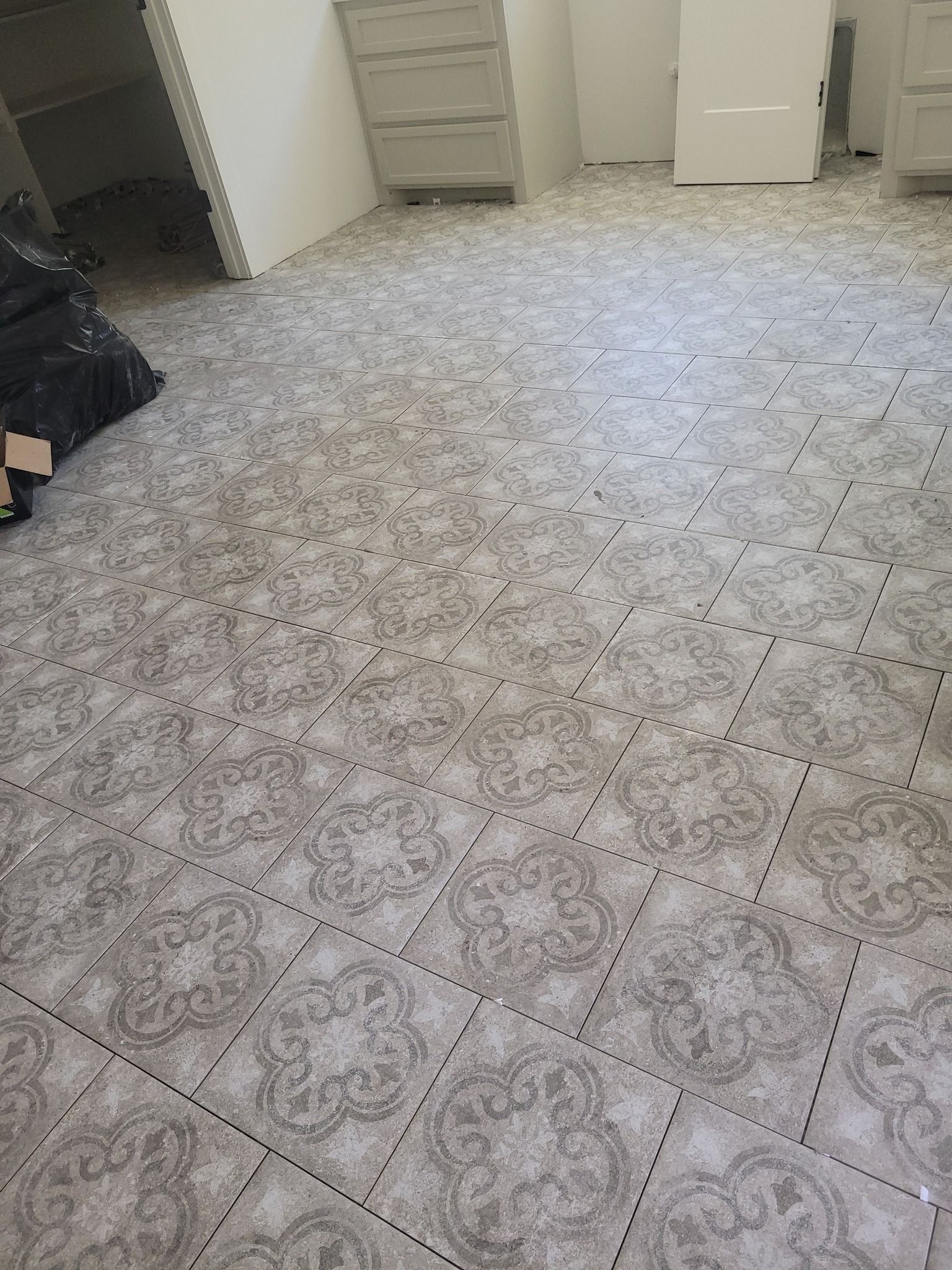 Empty room with patterned tile floor, white walls, and a small open closet area