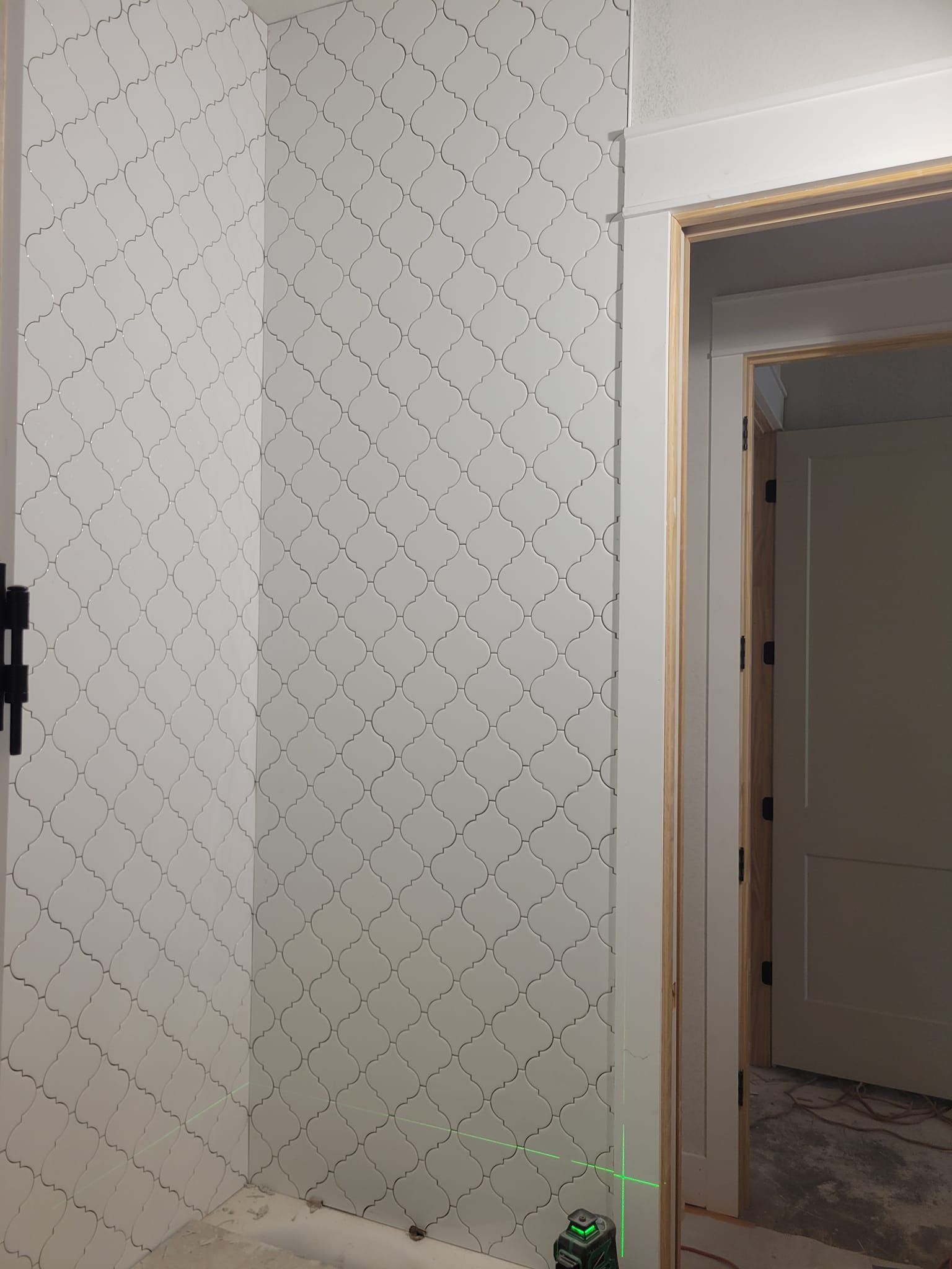 Interior hallway with patterned white walls and an open doorway with white trim and gold accents