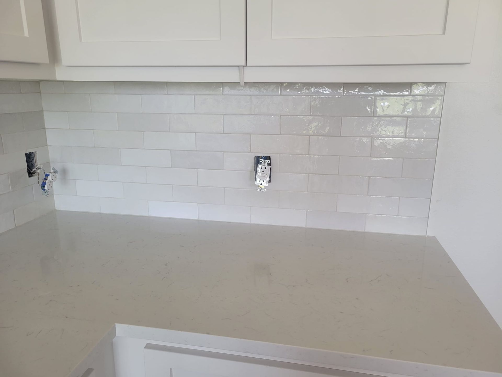 Empty kitchen countertop with white subway tile backsplash and white cabinets
