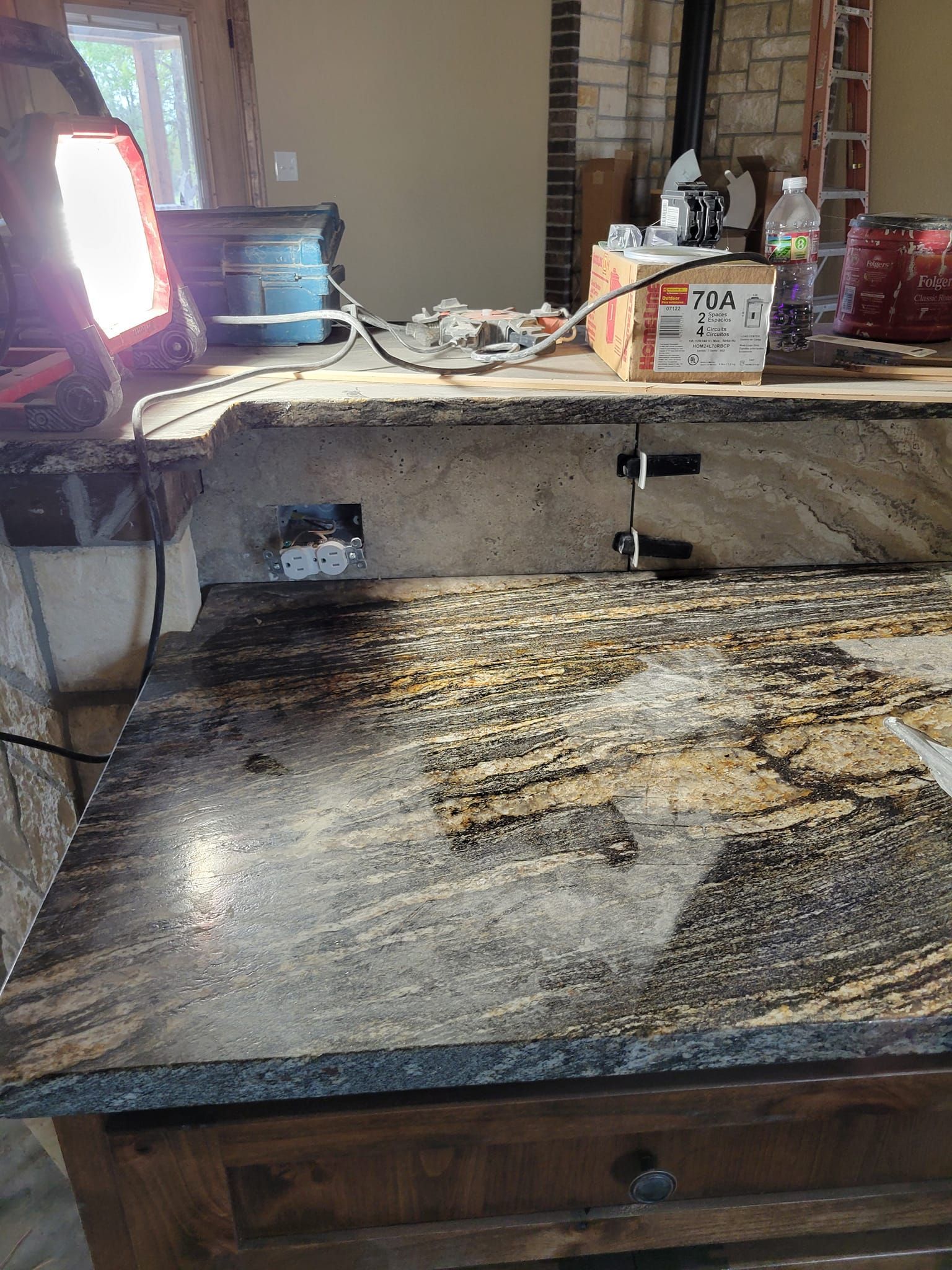 Kitchen sink countertop with scattered debris, a bright monitor on the left, and clutter on the back ledge