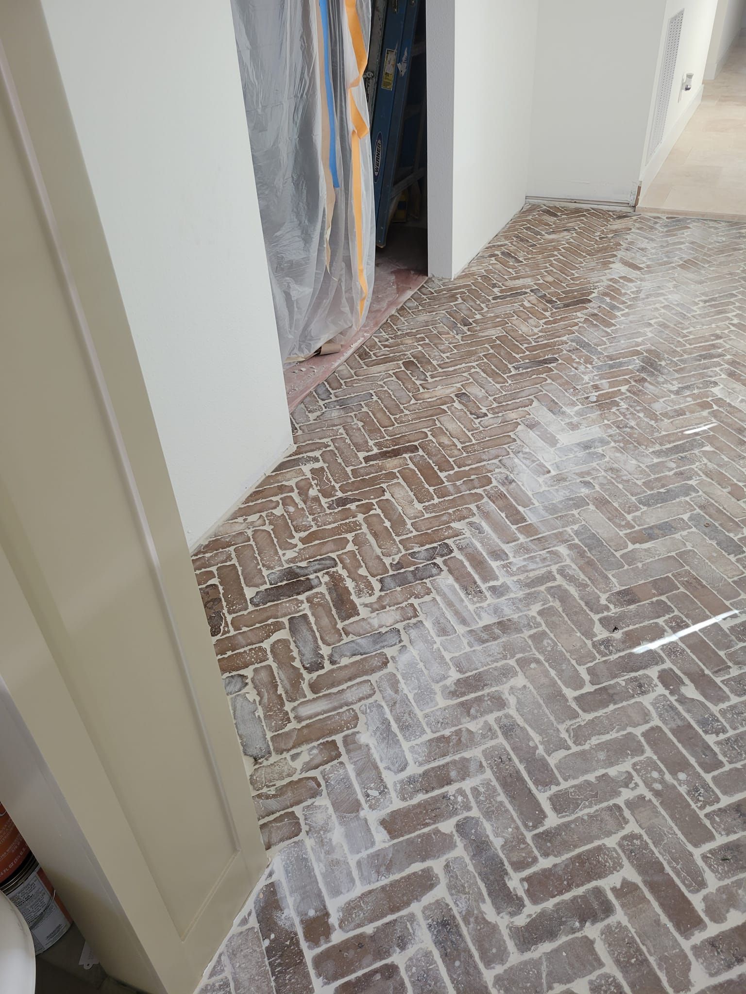Hallway with a partially finished brick-pattern floor and open doorway