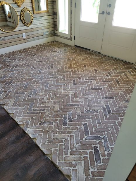Brick herringbone floor in a bright entryway with white doors and windows.