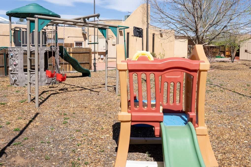 Playground with brown structures and a green slide in a yard.