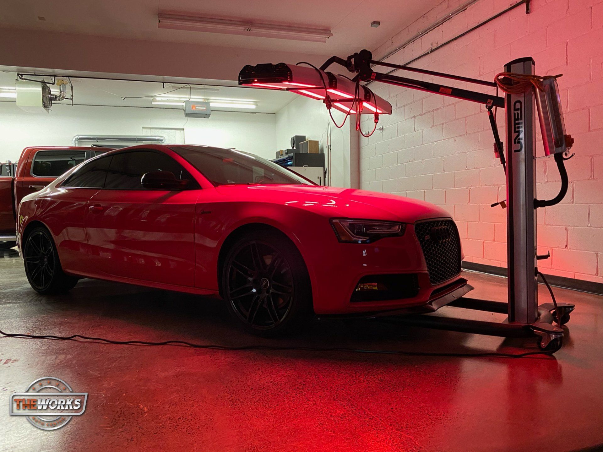 Red car inside a garage under infrared lights.