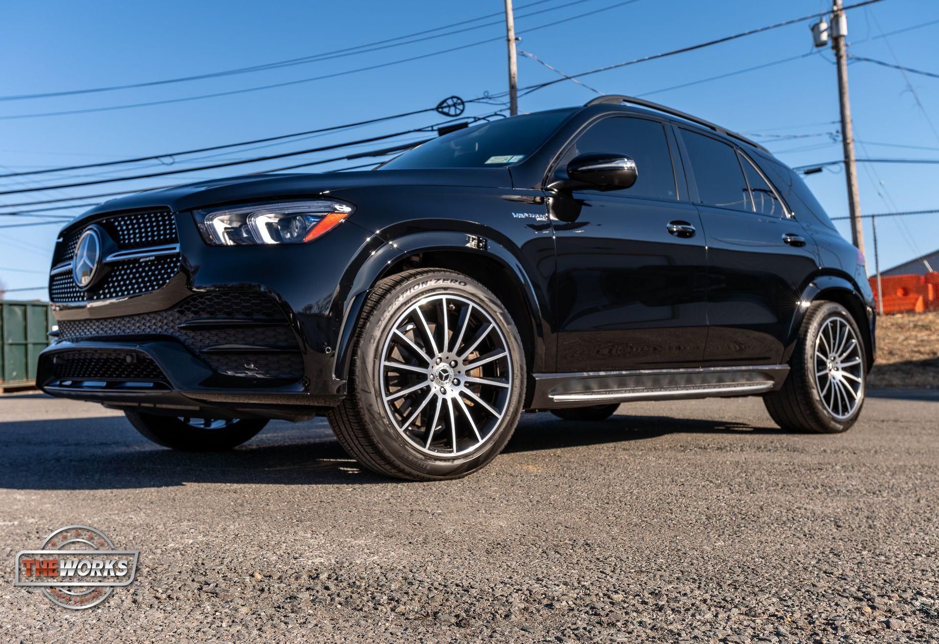 Black SUV parked on pavement under a blue sky, front three-quarter view with chrome wheels.