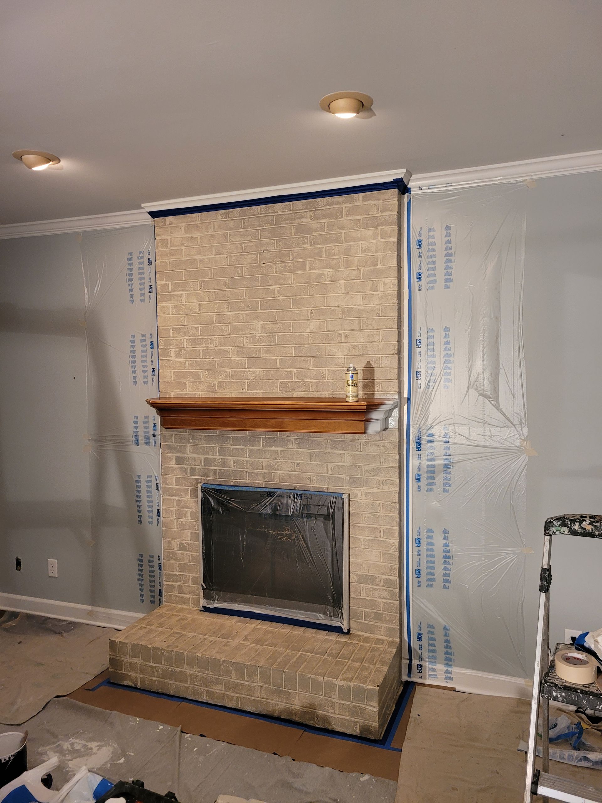 Unfinished living room with a stone fireplace under construction and protective floor covering.
